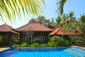 a villa with a swimming pool in front of a house at Nyoman Guesthouse and Grill in Nusa Lembongan