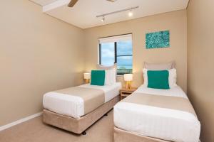 two beds in a room with a window at Saltwater Suites - 1,2 & 3 Bed Waterfront Apartments in Darwin