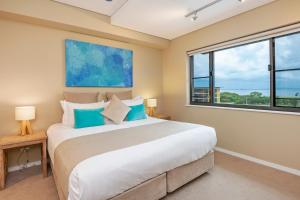 a bedroom with a large bed and two windows at Saltwater Suites - 1,2 & 3 Bed Waterfront Apartments in Darwin