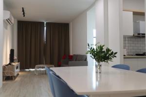 sala de estar con mesa blanca y sillas azules en Zen66 @ Roxy Serviced Apartment, en Kuching