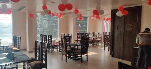 a dining room with tables and chairs and red balloons at Hotel Trimurti in Haridwār