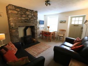 a living room with a couch and a stone fireplace at Back Cottage in Kirkby Lonsdale