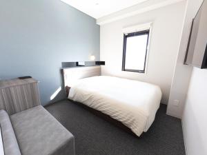 a bedroom with a white bed and a window at Super Hotel Ishikawa Nomineagari Smart Inter in Nomi