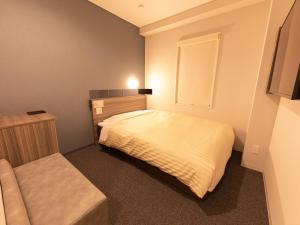 a small bedroom with a bed and a window at Super Hotel Ishikawa Nomineagari Smart Inter in Nomi