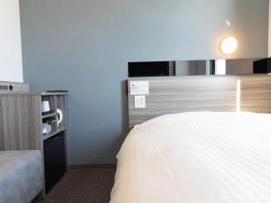 a hotel room with a bed and a tv at Super Hotel Ishikawa Nomineagari Smart Inter in Nomi