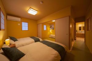 a hotel room with two beds and a bathroom at Yufuin Matsuri-an Nagomiya in Yufuin