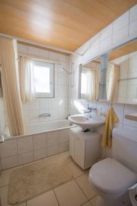 een badkamer met een toilet, een wastafel en een bad bij Chalet Apollo in Adelboden