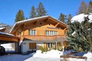 Casa de madera grande con nieve en el suelo en Chalet Apollo en Adelboden