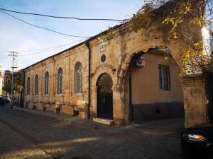 un antiguo edificio de piedra con un arco en una calle en 1870 Hotel en Kutaisi