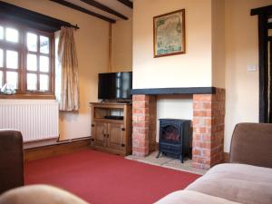 a living room with a fireplace and a tv at Yew Tree Cottage in Great Malvern