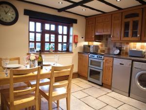 a kitchen with a table and chairs and a clock at Yew Tree Cottage in Great Malvern