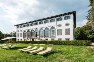 un gruppo di sedie a sdraio di fronte a un edificio di Villa Guinigi Dimora di Epoca Exclusive Residence & Pool a Lucca