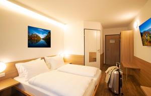 a bedroom with a white bed and a painting on the wall at OEKOTEL Hohenems in Hohenems