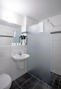 a white bathroom with a toilet and a sink at OEKOTEL Hohenems in Hohenems