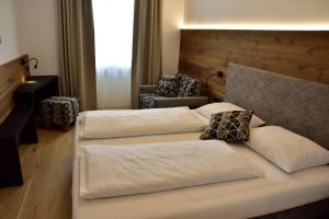1 Schlafzimmer mit 2 Betten und einem Stuhl in der Unterkunft Hotel Krone in Bruneck