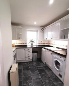 a kitchen with white cabinets and a washer and dryer at Seaside Apartment in Oban