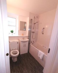 a bathroom with a toilet and a tub and a sink at Seaside Apartment in Oban