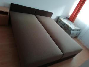 a brown couch sitting in a corner of a room at Horváth Apartman in Cserkeszőlő