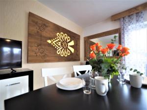 a dining room table with a vase of orange flowers on it at VIP Apartamenty KRUPÓWKI in Zakopane