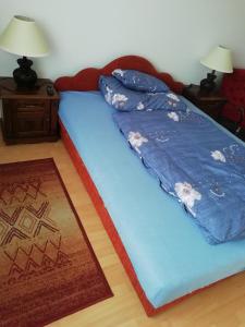 a bed with a blue comforter on it in a room at Horváth Apartman in Cserkeszőlő
