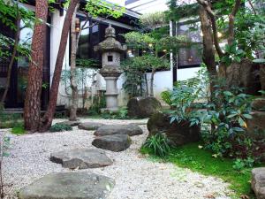 un giardino con sentiero in pietra di fronte a un edificio di Oyado Yamakyu a Takayama