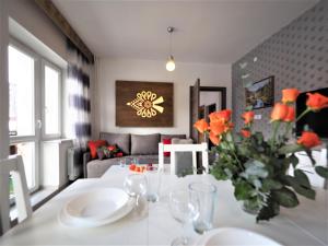 a living room with a table with a vase of orange flowers at VIP Apartamenty KRUPÓWKI in Zakopane