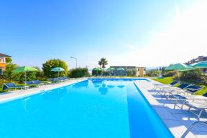 une grande piscine avec des chaises et des parasols dans l'établissement Relais Rosa Dei Venti -Ciao Vacanze-, à Moniga del Garda