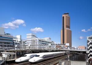 Dos trenes blancos sobre las vías en una ciudad en Okura Act City Hotel Hamamatsu, en Hamamatsu