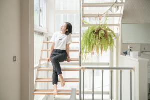 a woman sitting on a ladder in a room at 365.Hostel in Tainan