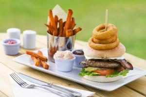 a plate with a hamburger with onion rings and french fries at Trethorne Hotel & Golf Club in Launceston