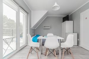 a dining room with white chairs and a table and a balcony at WILLA MORSKA Beach Apartment in Sztutowo