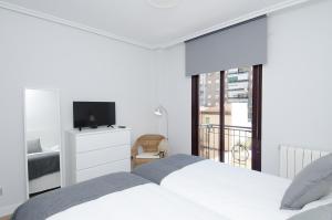 een witte slaapkamer met een bed en een televisie bij Apartamento Salamanca VI en Madrid in Madrid