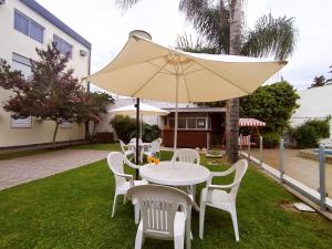 uma mesa branca e cadeiras com um guarda-sol em Gran Lourdes Hotel by CPH em Villa Carlos Paz