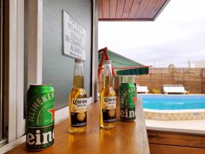 three bottles of beer sitting on a table near a pool at Gran Lourdes Hotel by CPH in Villa Carlos Paz