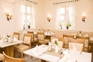 a restaurant with white tables and chairs and windows at Lindenhaus Scharfe Kurve in Rosenow