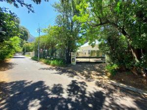 a tree lined street with a fence and a driveway at Newlands Guest House in Cape Town