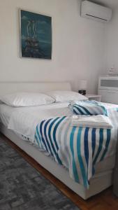 białe łóżko z paskowym kocem w obiekcie apartman-maja-krk w Krku