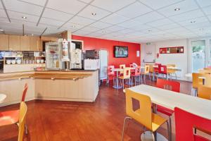 a restaurant with red walls and tables and chairs at Premiere Classe Cergy Saint Christophe in Cergy