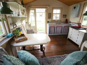 a kitchen with a table in a tiny house at Zoute Bries, in Natuurgebied en vlakbij het Strand in Callantsoog