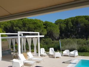 - un groupe de chaises blanches et une piscine dans l'établissement Appartamenti Giglio di Mare, à Policoro