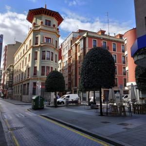 a city street with buildings and tables and trees at Hostel GoodHouse Gijón in Gijón