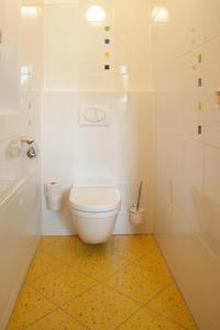 bagno con servizi igienici bianchi e pavimento giallo di Raiffeisenhof Appartements a Ehrenhausen