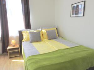 a bed with a green and yellow sheets and pillows at Apartments CITY Stadion in Linz