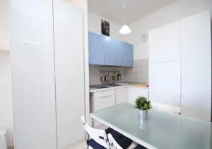 uma cozinha com uma mesa e alguns armários brancos em Appartamento Sul Mare em Teulada
