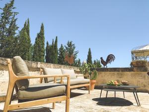 a patio with two chairs and a table and a chicken statue at Masseria Marzalossa in Fasano