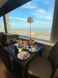 una mesa con comida y vistas a la playa en Hotel De La Plage en Quiberville