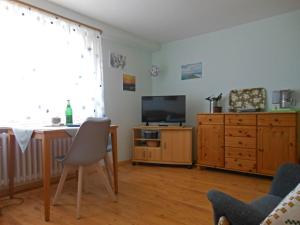 ein Wohnzimmer mit einem Tisch, einem TV und einem Schreibtisch in der Unterkunft Ferienhaus Heißer Sand, Whg 2 in Wittdün
