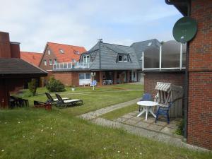 einen Hinterhof eines Hauses mit einem Tisch und Stühlen in der Unterkunft Ferienhaus Heißer Sand, Whg 2 in Wittdün