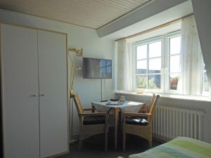 ウィトデュンにあるFerienhaus-Heisser-Sand-Whg-6のテーブルと椅子、窓が備わる客室です。