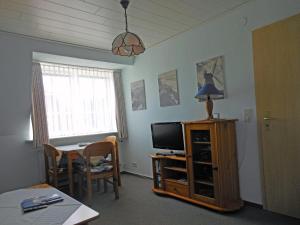 ein Wohnzimmer mit einem TV und einem Tisch sowie ein Esszimmer in der Unterkunft Ferienhaus "Heißer Sand", Whg 7 in Wittdün